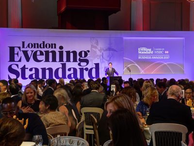 A formal event with attendees facing a stage with "London Evening Standard Business Awards 2017" signage.